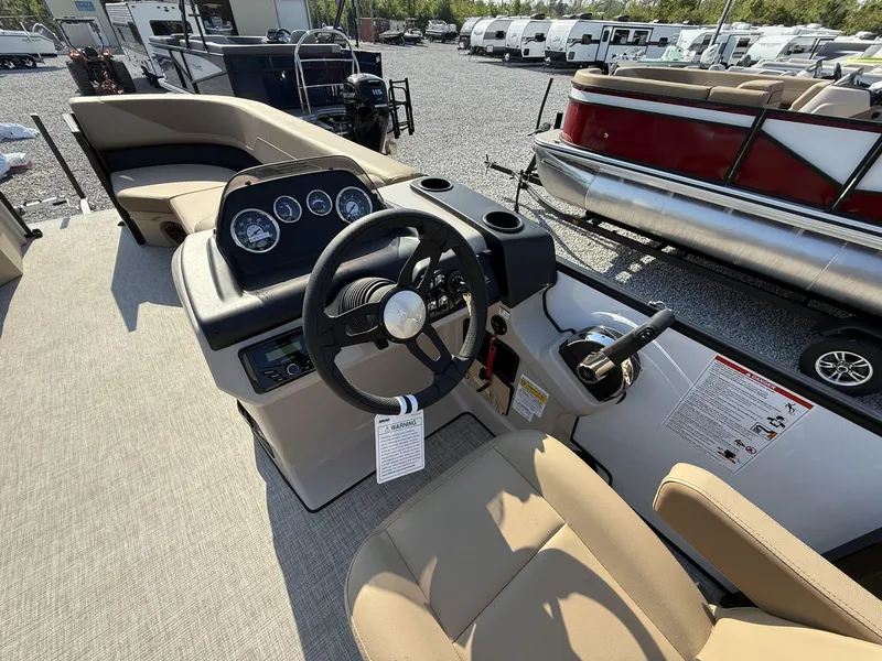 Slide: The Image of 2025 Lowe LS 210 boat interior with steering console and seating, parked in a lot. - 3