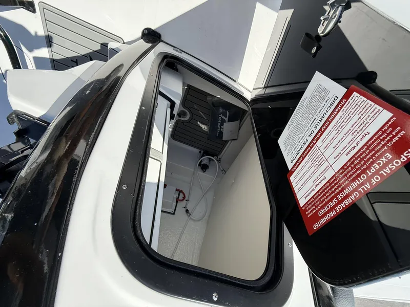 Slide: The Image of 2025 Tidewater 2410 Bay Max boat storage compartment with open hatch and safety instructions. - 12