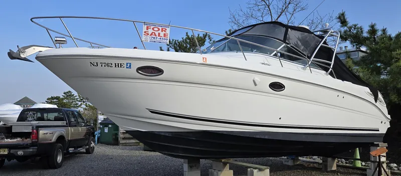 Slide: The Image of 2005 Sea Ray 290 Amberjack boat for sale, parked on blocks, with a "For Sale" sign. - 2