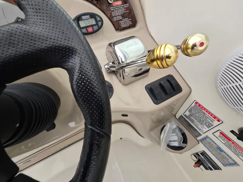 Slide: The Image of 2005 Sea Ray 290 Amberjack helm controls with steering wheel and throttle levers. - 27
