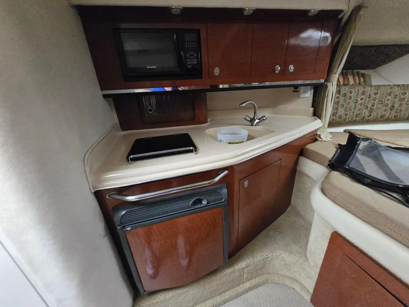 Slide: The Image of 2005 Sea Ray 290 Amberjack cabin kitchen with microwave, sink, and storage cabinets. - 31