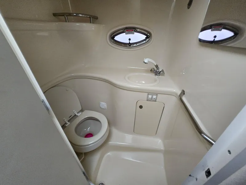 Slide: The Image of 2005 Sea Ray 290 Amberjack bathroom with toilet, sink, and porthole windows. - 33