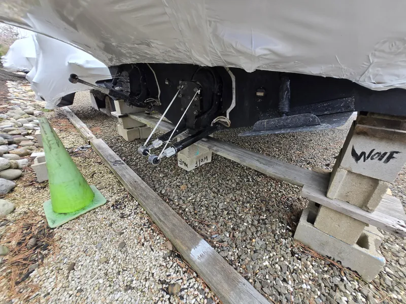 Slide: The Image of 2005 Sea Ray 290 Amberjack boat on blocks, covered, with visible outdrive and green cone nearby. - 36