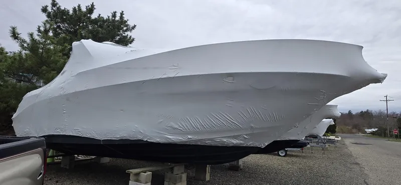 Slide: The Image of 2005 Sea Ray 290 Amberjack boat covered in protective wrap, parked on gravel. - 46