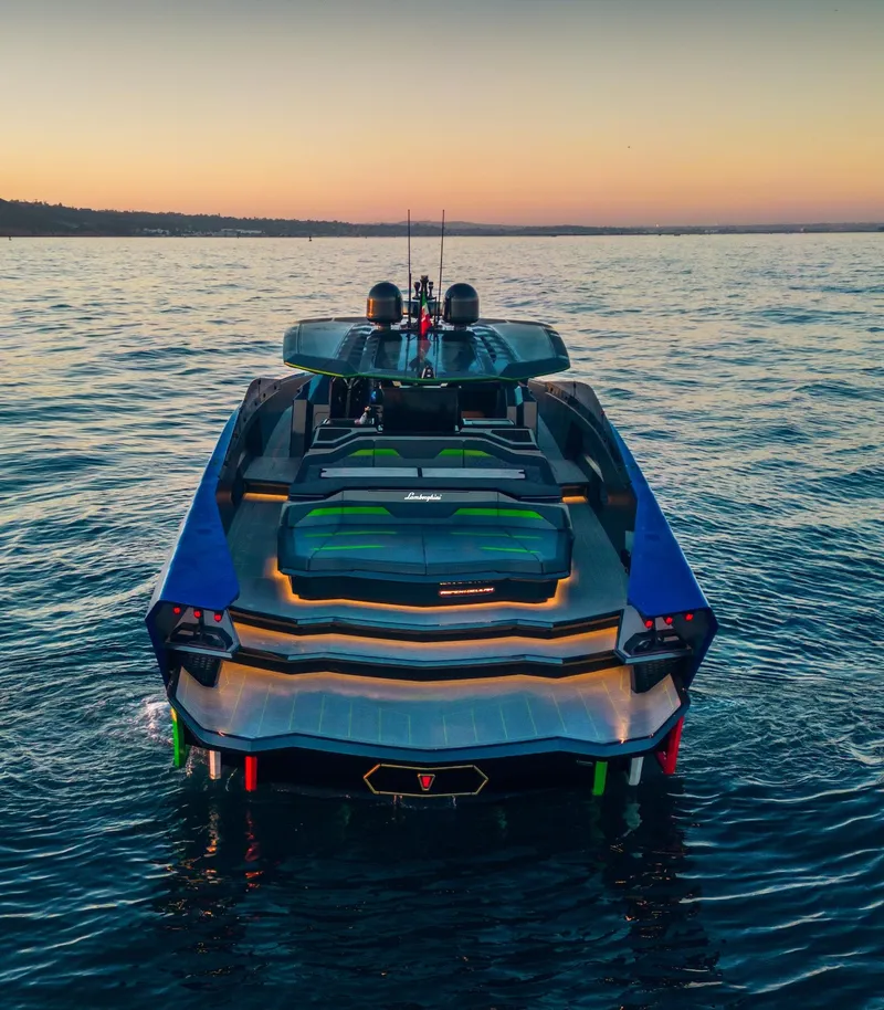 Slide: The Image of 2023 Tecnomar Lamborghini 63 yacht on serene water at sunset. - 2