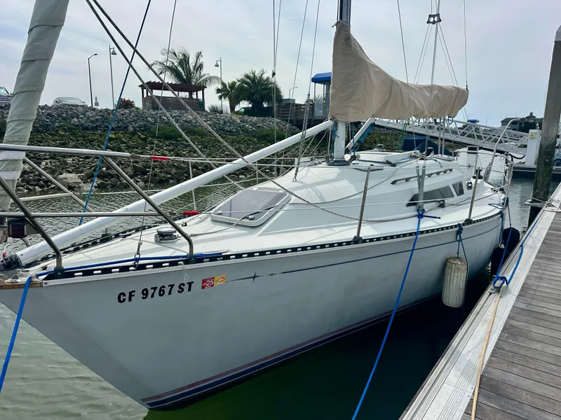 Slide: The Image of 1988 C&C MKII sailboat docked at marina with palm trees in background. - 2