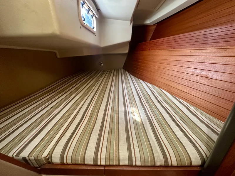 Slide: The Image of 1988 C&C MKII boat cabin with striped bedding and wooden paneling. - 22