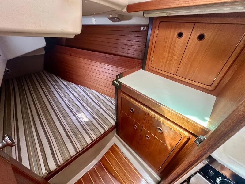Slide: The Image of Interior of 1988 C&C MKII sailboat with wood cabinetry and striped bedding. - 23