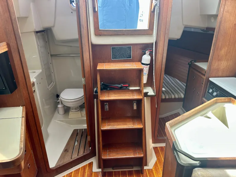 Slide: The Image of 1988 C&C MKII yacht interior with wooden steps, bathroom, and cozy cabin space. - 25