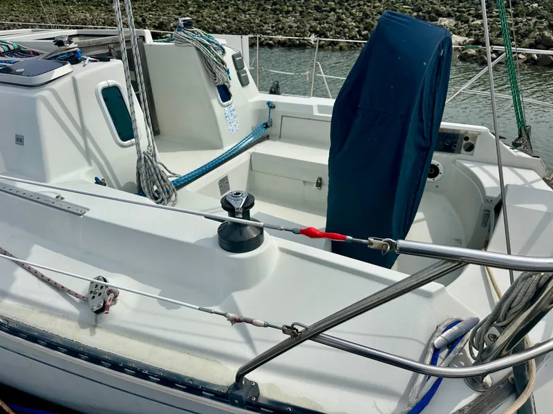 Slide: The Image of 1988 C&C MKII sailboat cockpit with covered wheel, ropes, and winch by the water. - 3