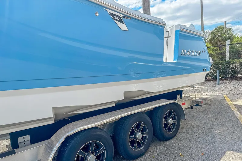 Slide: The Image of 2023 Blackfin 302CC boat on trailer, blue and white exterior, parked outdoors. - 3