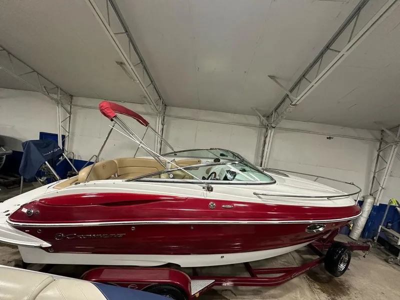 Slide: The Image of 2015 Crownline 236 SC boat with red and white exterior in indoor storage. - 2