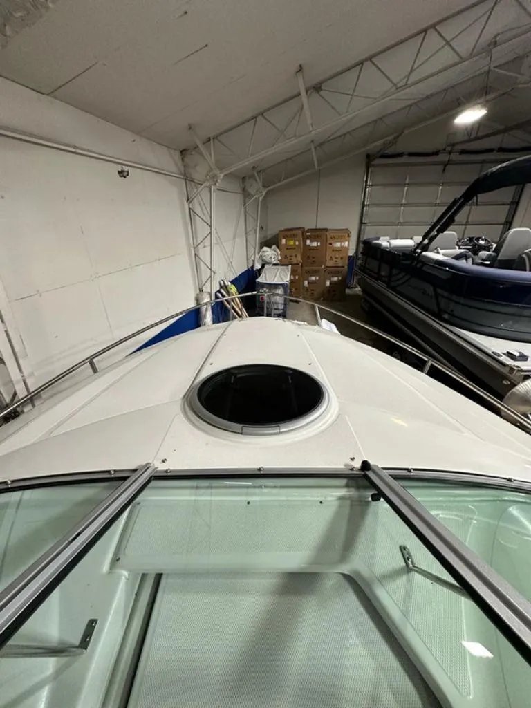 Slide: The Image of 2015 Crownline 236 SC boat in indoor storage, showing front deck and hatch. - 8