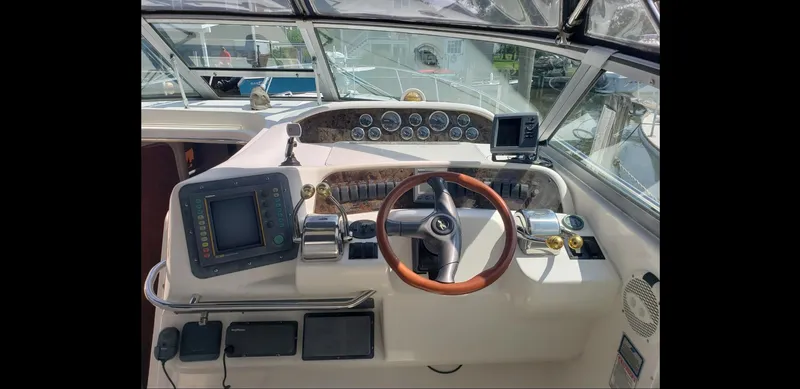 Slide: The Image of 1999 Sea Ray 330 Sundancer helm with wooden steering wheel and navigation instruments. - 11