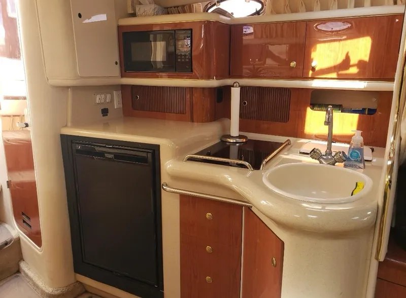 Slide: The Image of 1999 Sea Ray 330 Sundancer yacht kitchen with sink, stove, microwave, and cabinetry. - 12
