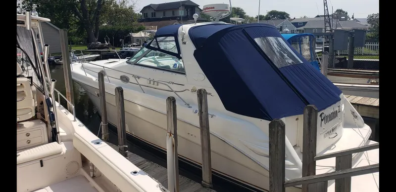 Slide: The Image of 1999 Sea Ray 330 Sundancer docked, featuring blue canopy and sleek design. - 2