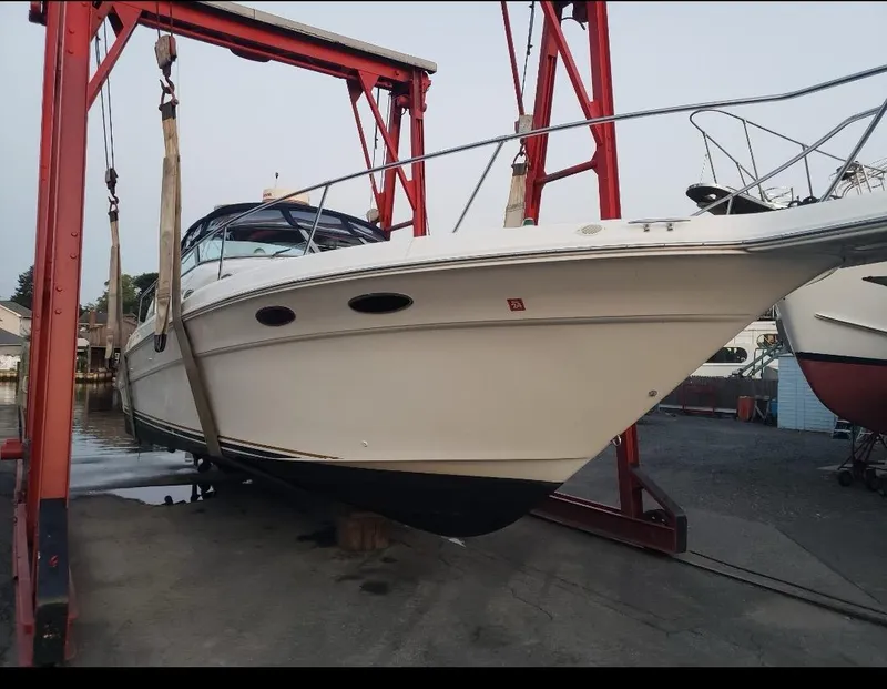 Slide: The Image of 1999 Sea Ray 330 Sundancer boat in dry dock, supported by red hoist. - 4