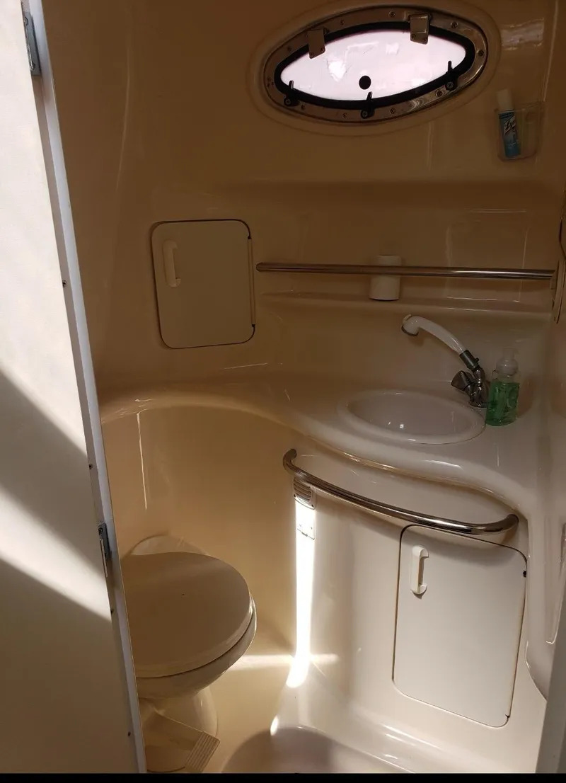 Slide: The Image of 1999 Sea Ray 330 Sundancer bathroom with sink, toilet, and porthole window. - 6