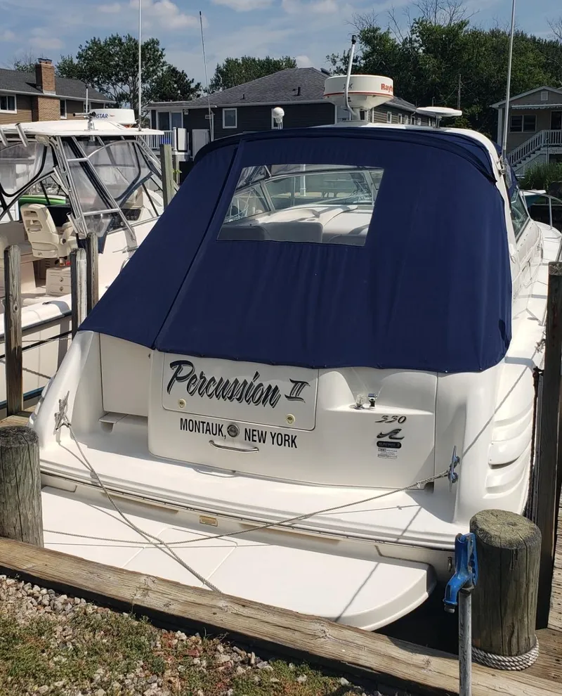 Slide: The Image of 1999 Sea Ray 330 Sundancer docked, featuring a blue cover and Montauk, New York registration. - 8