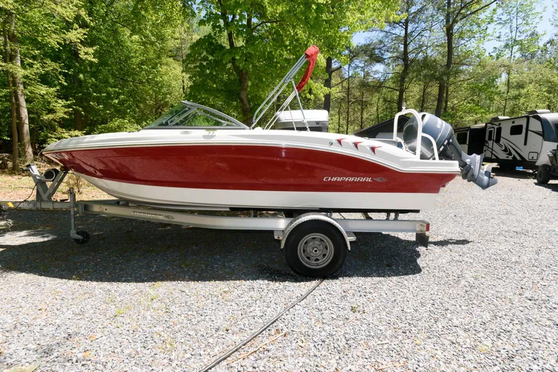 Slide: The Image of 2020 Chaparral 19 SSi OB boat on trailer, red and white, parked on gravel. - 0