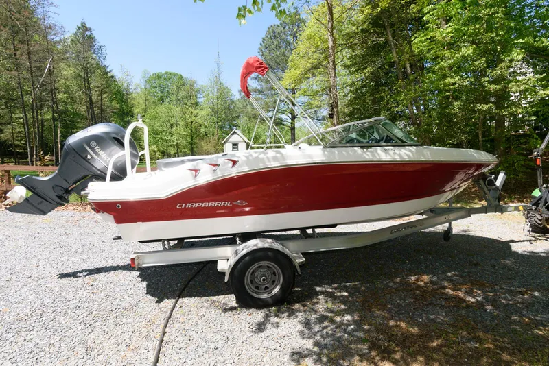 Slide: The Image of 2020 Chaparral 19 SSi OB boat on trailer, red and white, parked outdoors. - 2