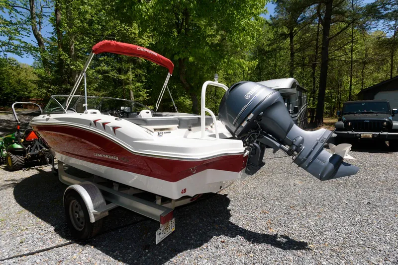 Slide: The Image of 2020 Chaparral 19 SSi OB boat on trailer, parked outdoors with trees in background. - 3