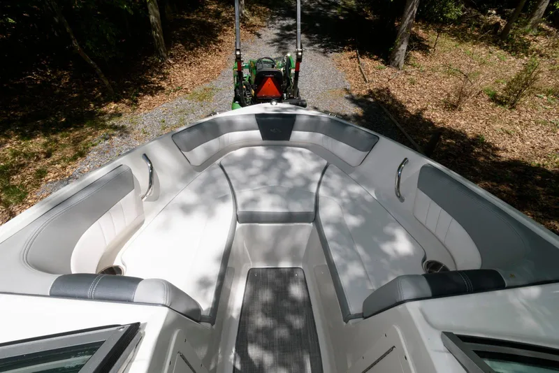Slide: The Image of 2020 Chaparral 19 SSi OB boat interior with cushioned seating, parked on a wooded path. - 8