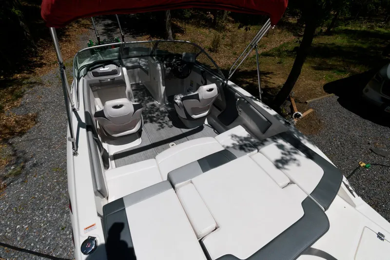 Slide: The Image of 2020 Chaparral 19 SSi OB boat interior with seating and canopy, parked on gravel. - 9