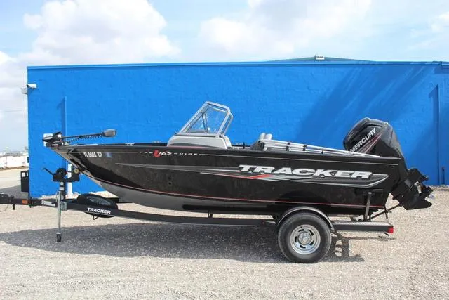 Slide: The Image of 2019 Tracker Pro Guide V-165 WT boat on trailer, parked near a blue wall. - 7