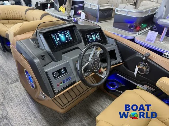 Slide: The Image of 2025 Tahoe Cascade 2385 Tritoon dashboard with modern controls and steering wheel at Boat World. - 13