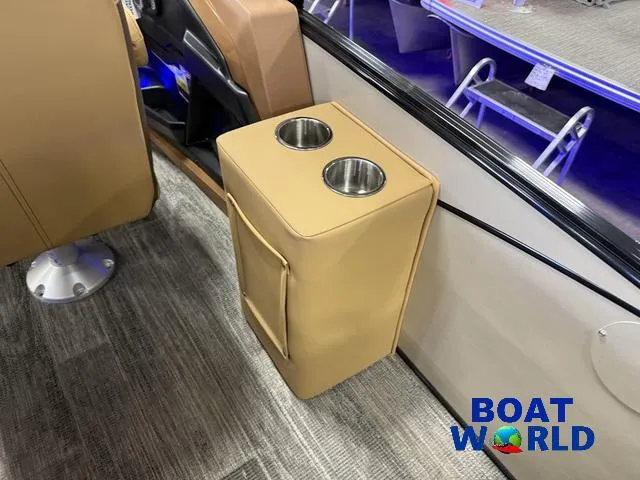 Slide: The Image of 2025 Tahoe Cascade 2385 Tritoon interior with dual cup holders, beige upholstery, and Boat World logo. - 26