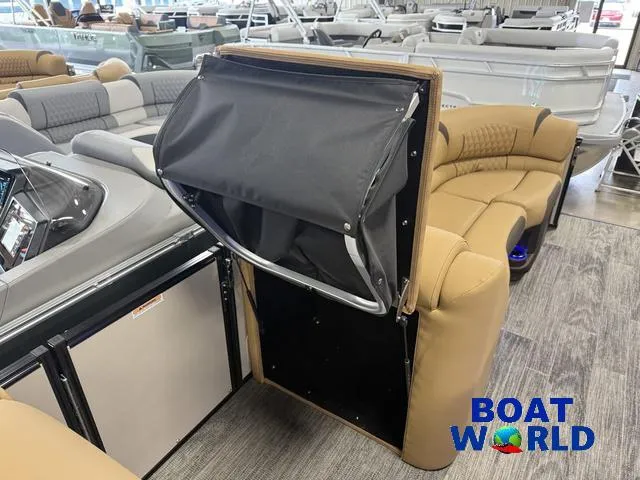 Slide: The Image of 2025 Tahoe Cascade 2385 Tritoon interior with tan seating and storage compartment at Boat World showroom. - 30