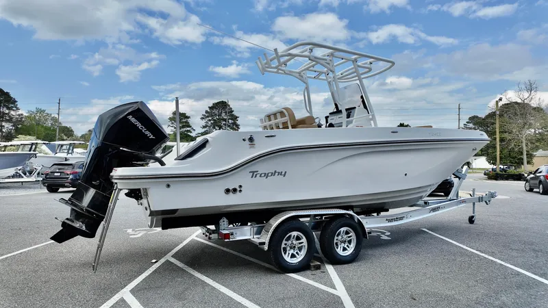 Slide: The Image of 2025 Bayliner Trophy 24 CC boat on trailer, parked outdoors under a cloudy sky. - 1