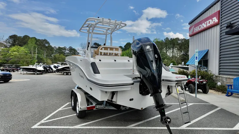 Slide: The Image of 2025 Bayliner Trophy 24 CC boat on trailer, parked outside a Honda dealership. - 2