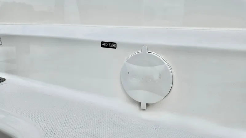 Slide: The Image of 2025 Bayliner Trophy 24 CC fresh water access point on white boat exterior. - 21