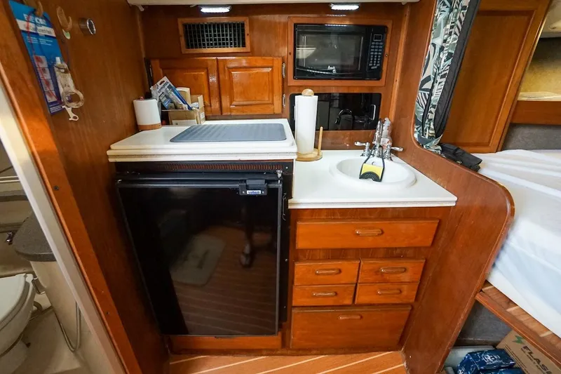 Slide: The Image of 1997 Luhrs Tournament 320 Open galley with sink, fridge, microwave, and wooden cabinetry. - 43