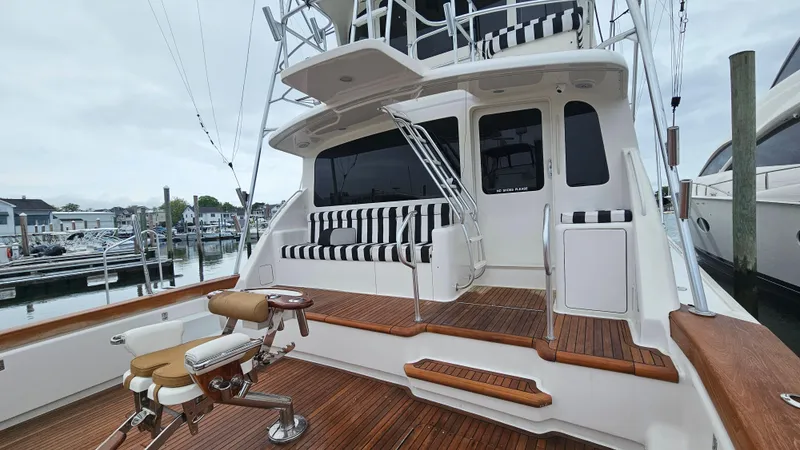 Slide: The Image of 2000 Ocean Yachts 70 Super Sport, spacious deck with striped seating, docked at marina. - 10