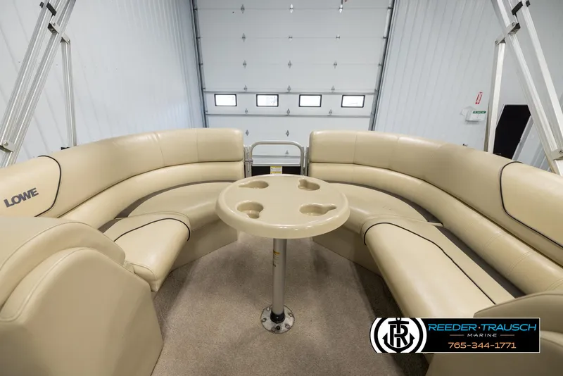 Slide: The Image of 2016 Lowe SS230 pontoon boat interior with beige seating and round table. - 22