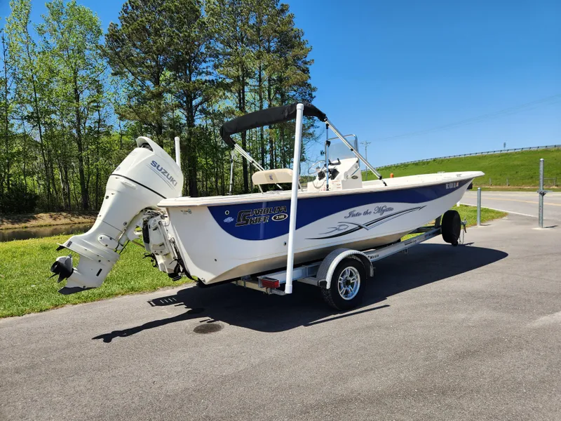 Slide: The Image of 2018 Carolina Skiff 218 DLV boat on trailer, parked outdoors on sunny day. - 2