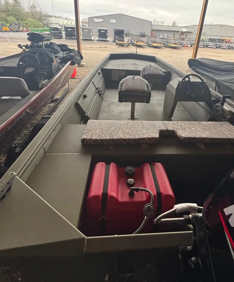 Slide: The Image of 2025 Lowe Roughneck 1860 boat with red fuel tank, parked under a shelter. - 7
