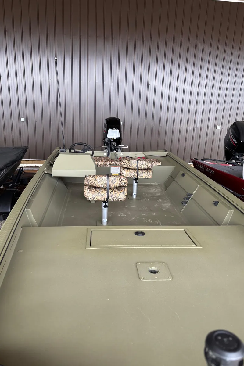 Slide: The Image of 2025 Lowe Roughneck 1860 boat with camouflage seating, parked indoors. - 8