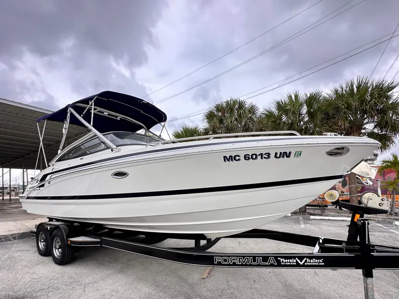 Slide: The Image of 2021 Formula 270 Bowrider boat on trailer, under cloudy sky, with palm trees in background. - 2