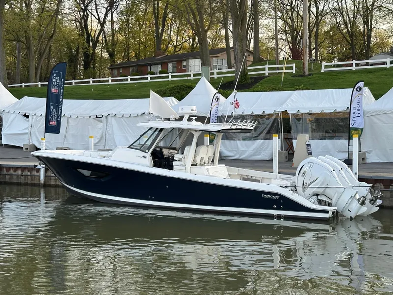 Slide: The Image of 2022 Pursuit S 378 Sport boat docked by a lakeside with tents and trees in the background. - 17