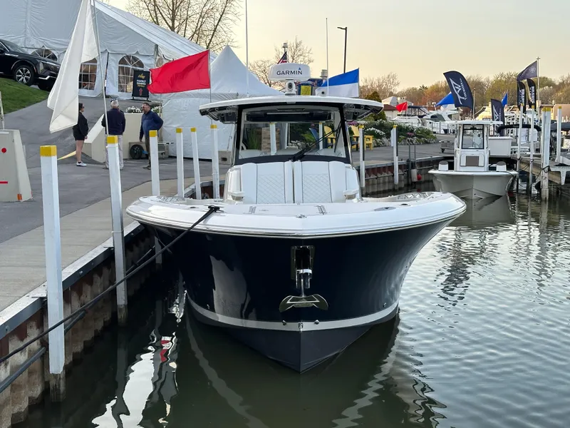 Slide: The Image of 2022 Pursuit S 378 Sport boat docked at marina, surrounded by flags and tents. - 19