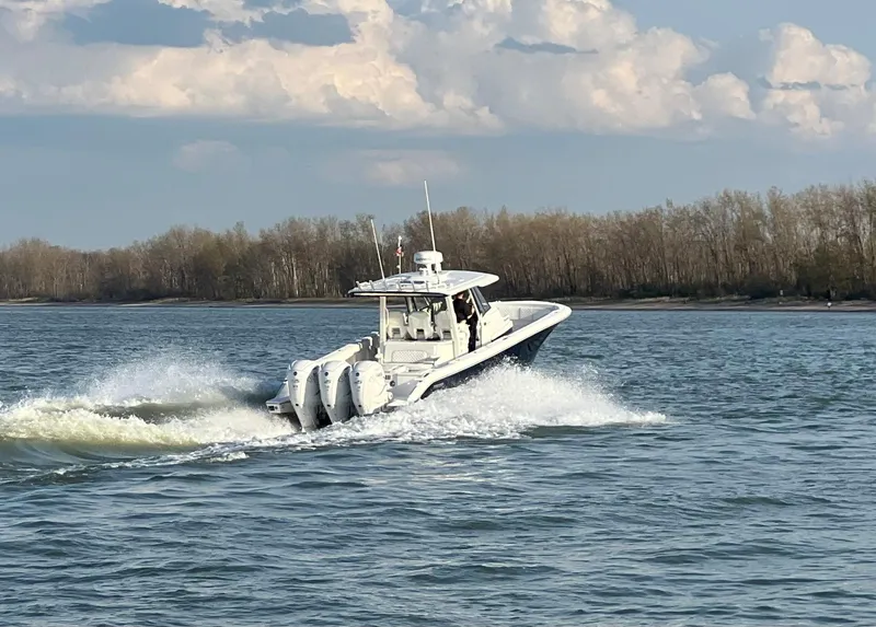 Slide: The Image of 2022 Pursuit S 378 Sport boat cruising on a lake with forested shoreline. - 4