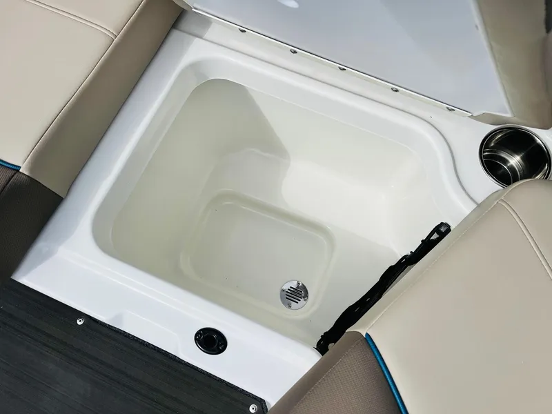 Slide: The Image of 2024 Tahoe 210 S Limited boat storage compartment with beige seating and cup holder. - 36