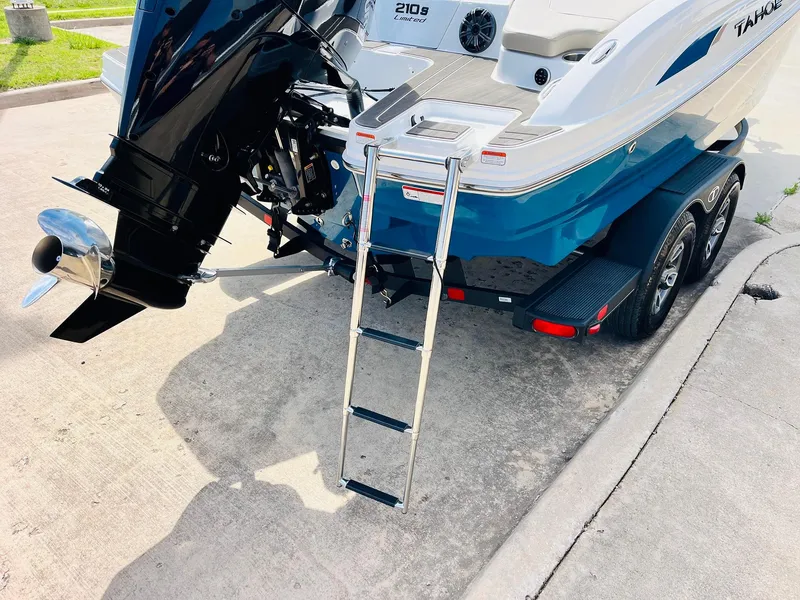 Slide: The Image of 2024 Tahoe 210 S Limited boat with ladder and trailer on pavement. - 9