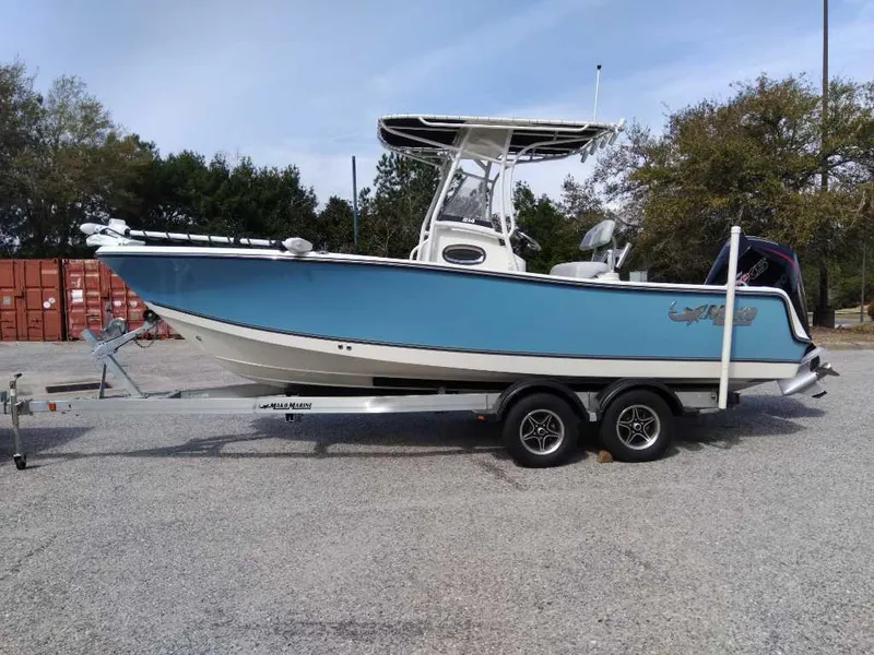 Slide: The Image of 2024 Mako 214 CC boat on trailer, blue hull, parked outdoors. - 4