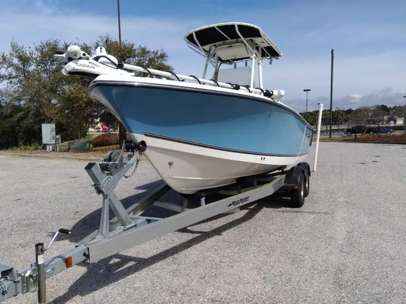 Slide: The Image of 2024 Mako 214 CC boat on trailer, blue and white hull, parked outdoors. - 5