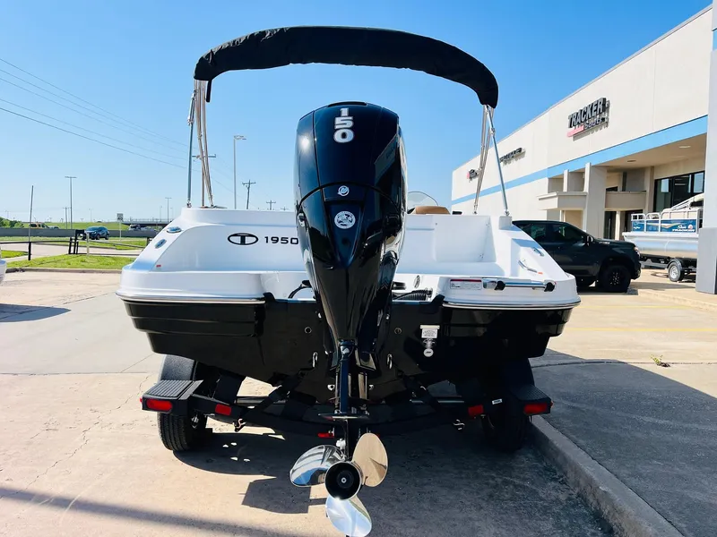 Slide: The Image of 2024 Tahoe 1950 boat with outboard motor, parked outdoors on a sunny day. - 7